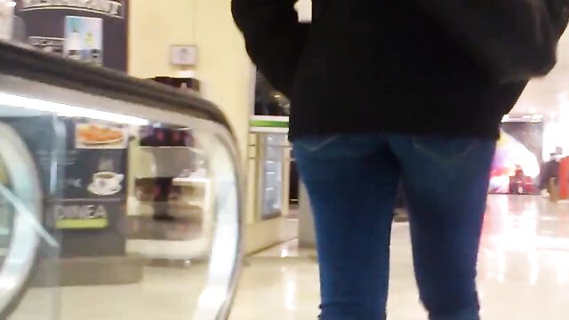 Молоденькая девушка в обтягивающих штанах гуляет по торговому центру